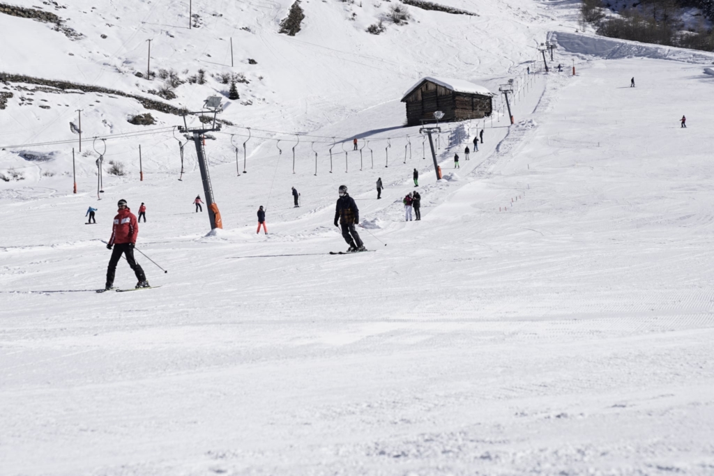 Skifahrer auf einer verschneiten Piste mit einem Skilift im Hintergrund