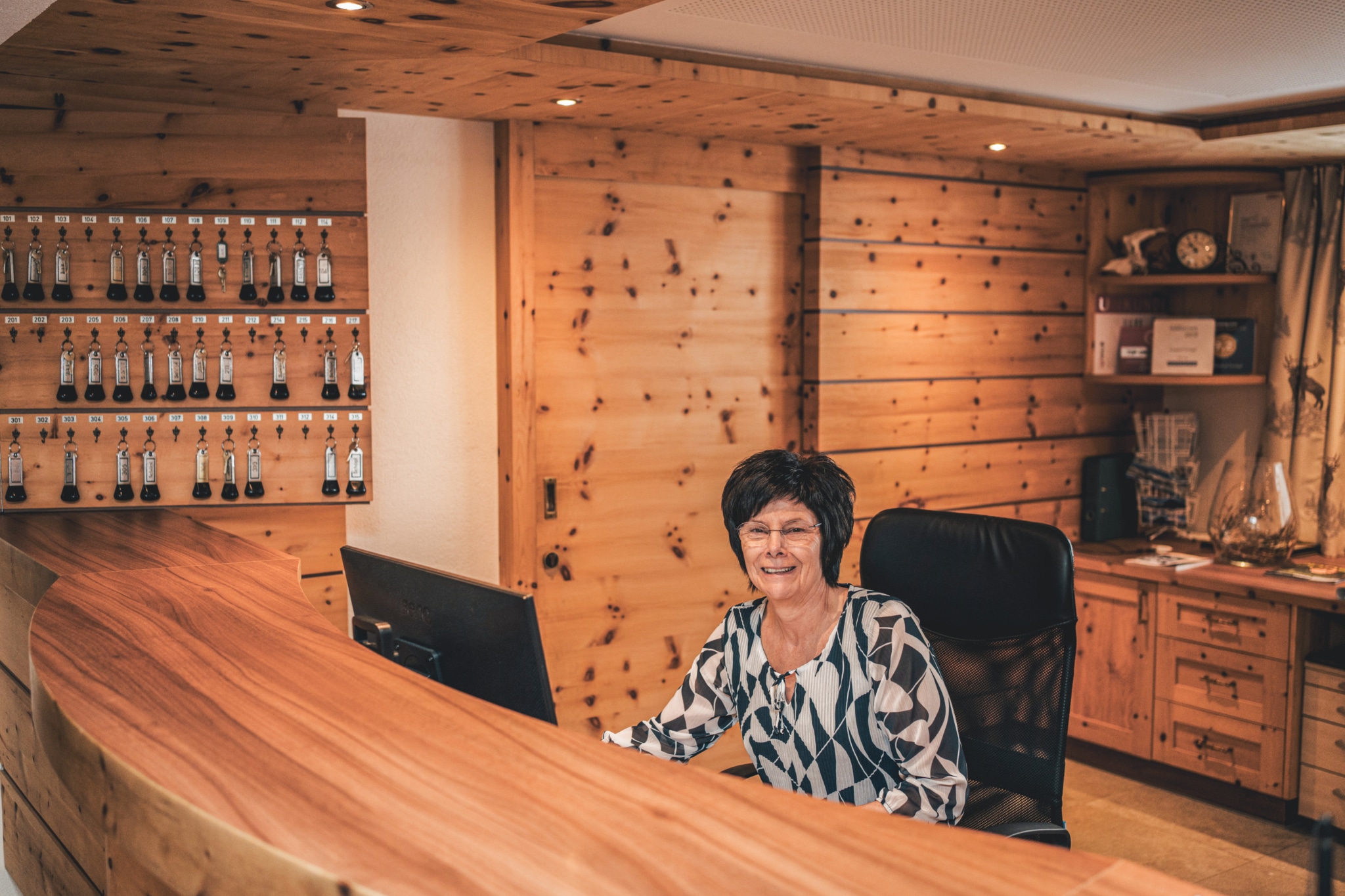 Friendly receptionist at a wooden reception desk