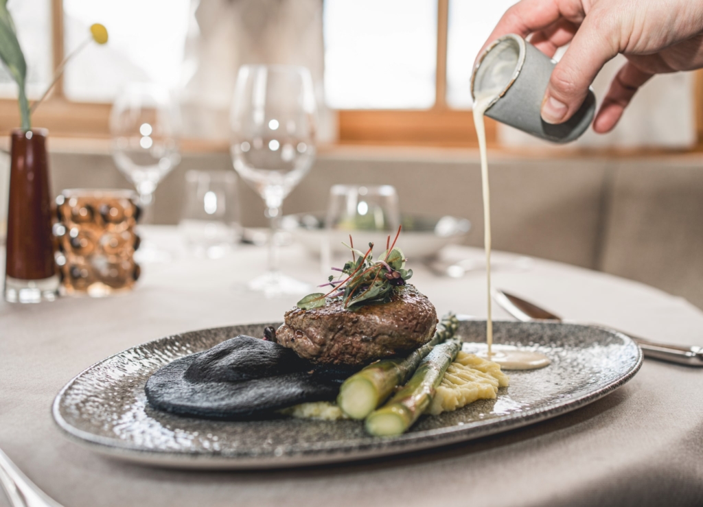 Ein delikates Rindersteak auf einem eleganten Teller mit grünem Spargel und einer cremigen Sauce